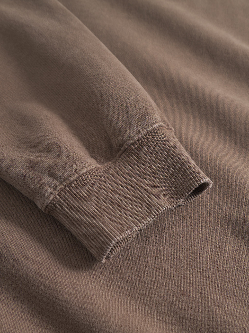 Close-up of the Gabba Volos Bump GWC sweatshirt in brown, featuring its super-soft fabric, ribbed cuff, and sleeve detail laid flat on a matching brown surface.