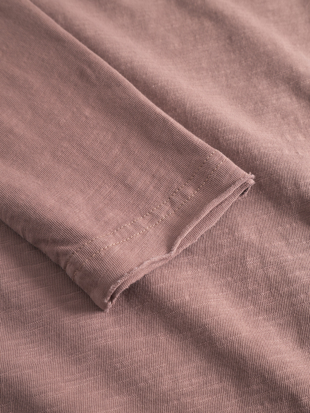 A close-up of the Gabba Paros Rif GWC - Rose highlights its mauve hue, fine stitching, super soft cotton, ribbed cuff texture, and subtle faded look on the long sleeve t-shirt.