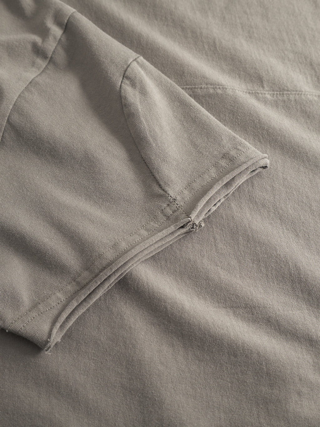 Close-up of the Gabba Idra Rig GWC - Grey tee laid flat, showcasing folded sleeve and seam details on ultra-soft cotton fabric.