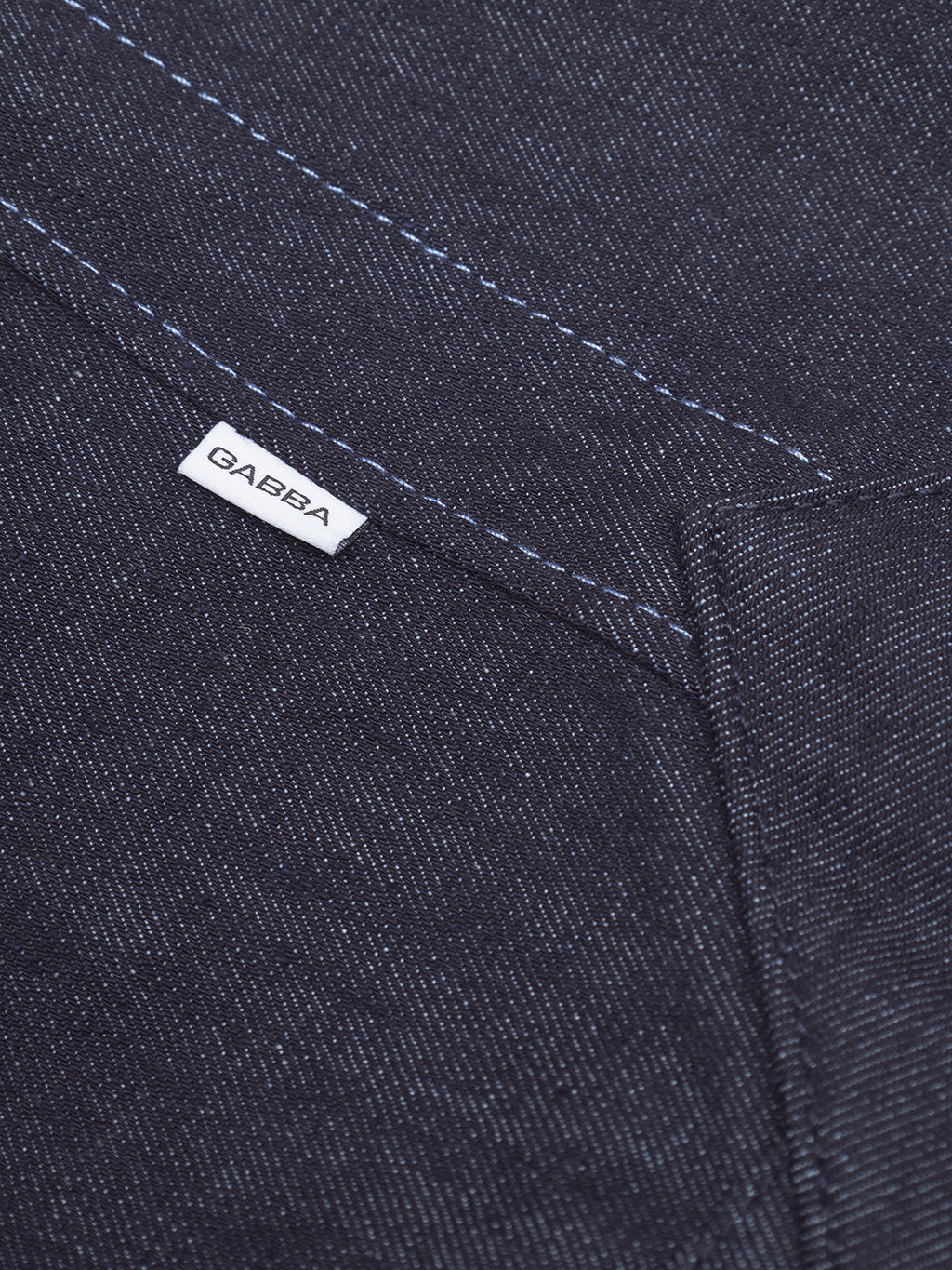 Close-up of Bag Self in dark blue denim by Gabba, featuring visible white stitching and a small white Gabba label near the pocket—crafted from recycled fibers for a modern, sustainable appeal.