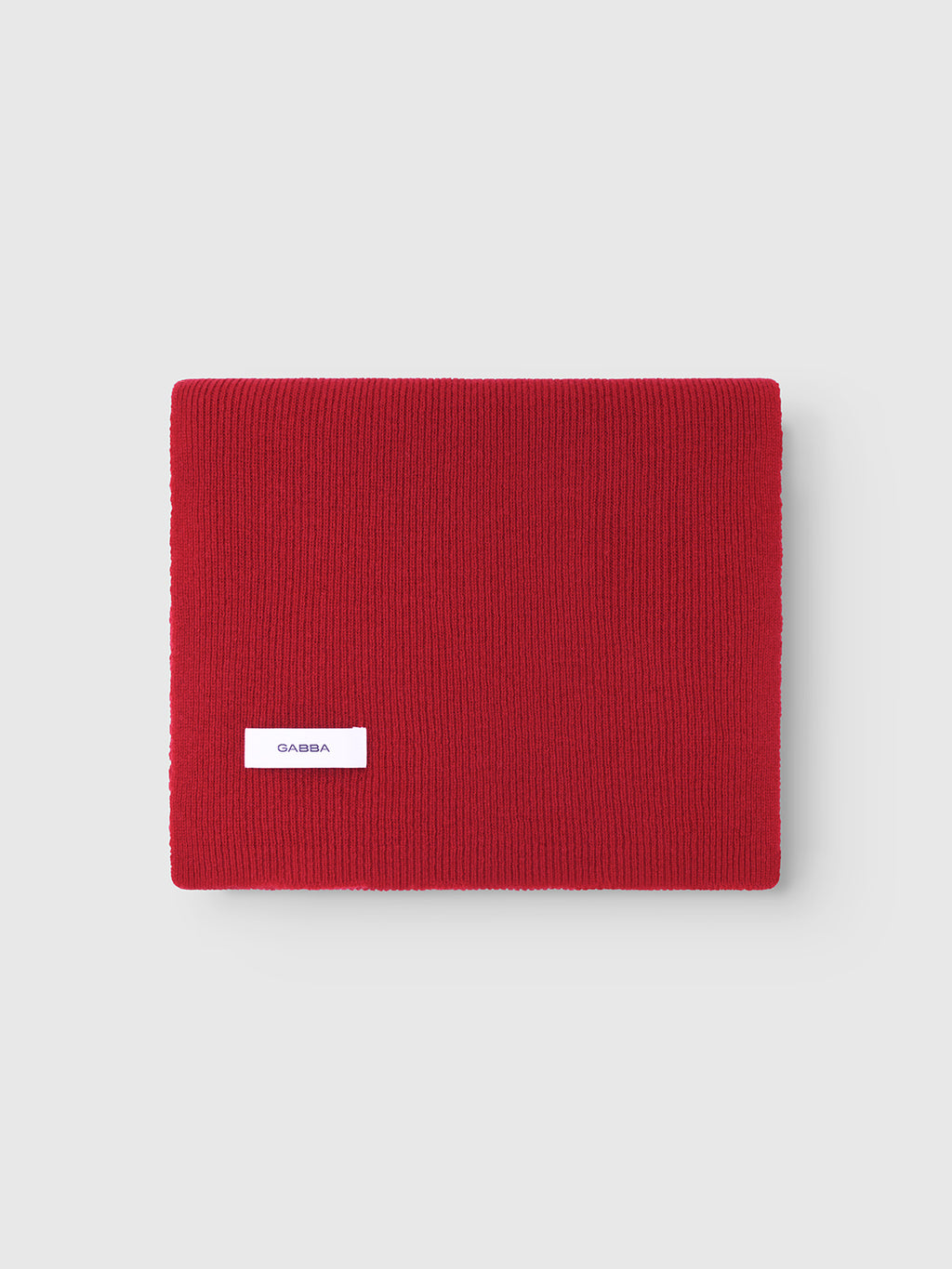 The Biwa Aico - Red by Gabba is a folded red scarf featuring a small white Gabba label, displayed on a light gray background—ideal for stylish winter wear.