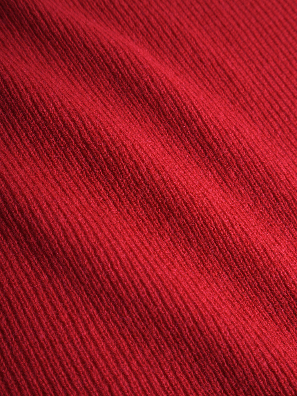 Close-up of the Biwa Aico - Red merino wool scarf by Gabba, highlighting ribbed fabric with diagonal textured lines and soft shadows that add depth and cozy warmth—an ideal winter accessory.