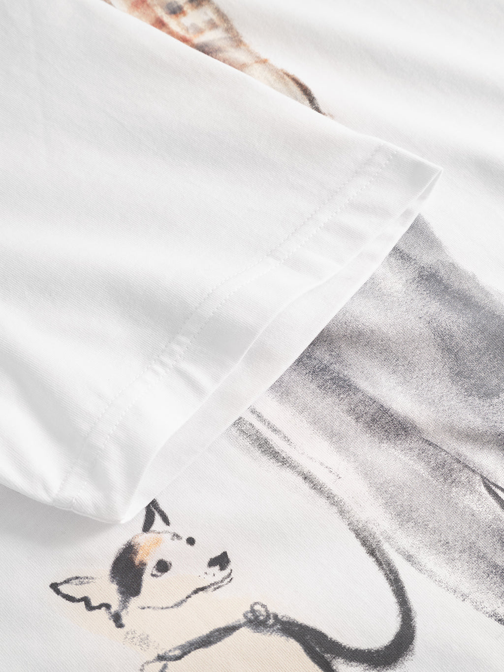 Close-up of the Gabba Dune Kay Man Bauw SS GOTS T-shirt in white, made from GOTS-certified organic cotton, featuring a printed small black and tan dog with a leash, partially concealed by the folded sleeve.