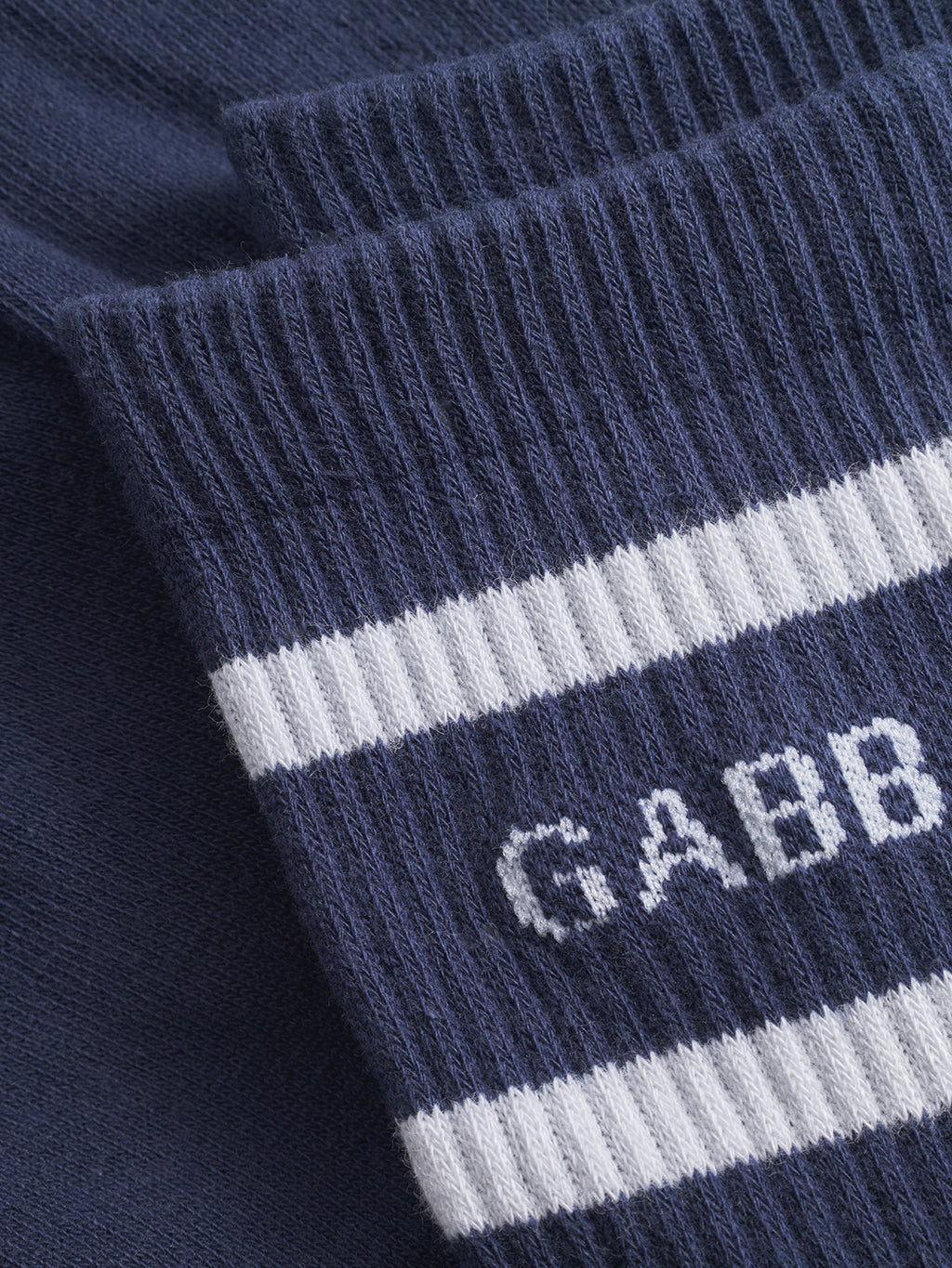Close-up of Gabba Zino Socks - Navy: ribbed cotton blend with white horizontal stripes and partial white GABB text. Solid navy section underneath adds comfort and style, perfect for everyday wear.