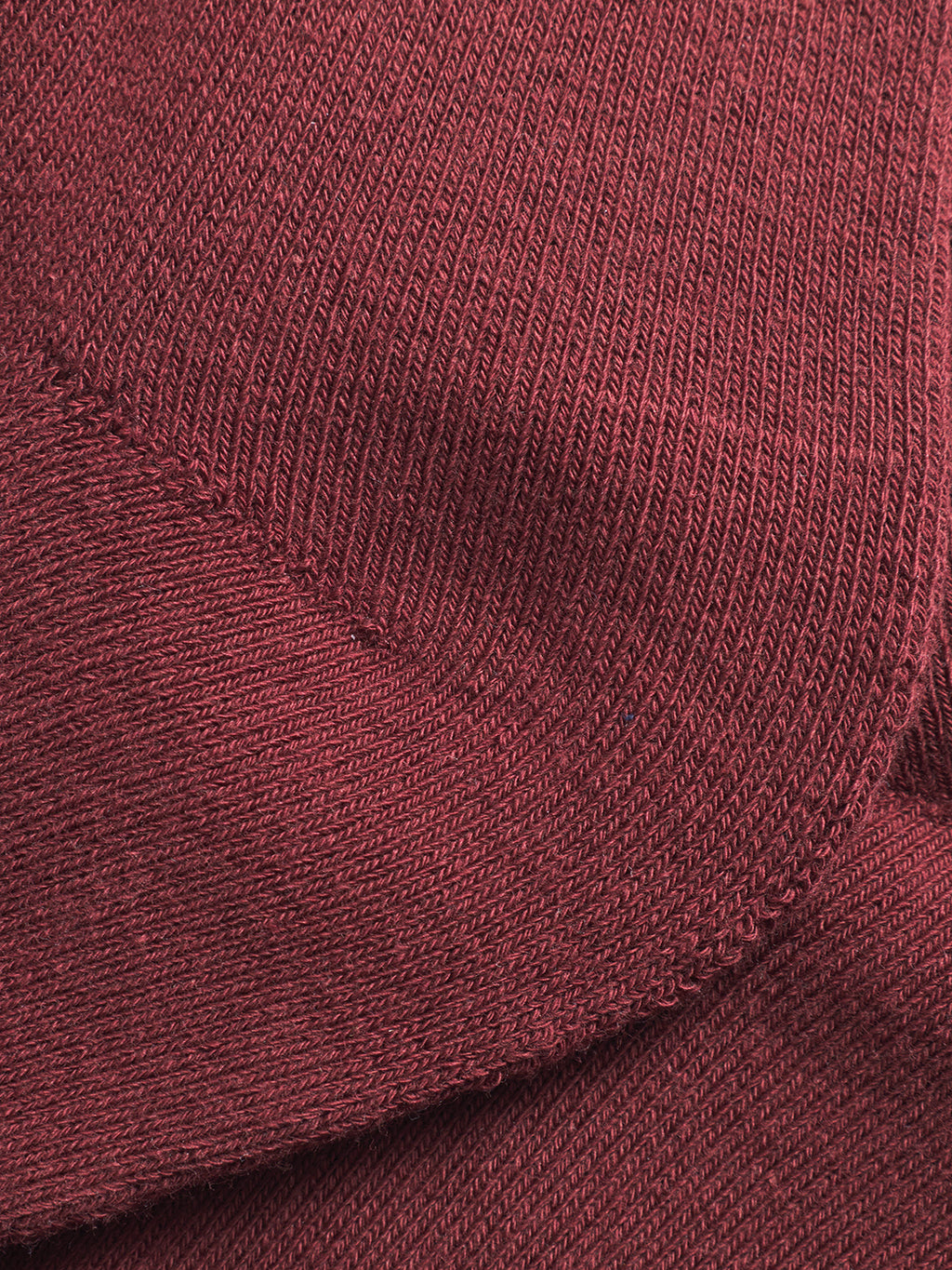Close-up of maroon knit fabric, showcasing the detailed texture and stitching of Gabba’s Zino Socks - Red Russet, known for their premium comfort and soft material—ideal for fans of richly colored socks.