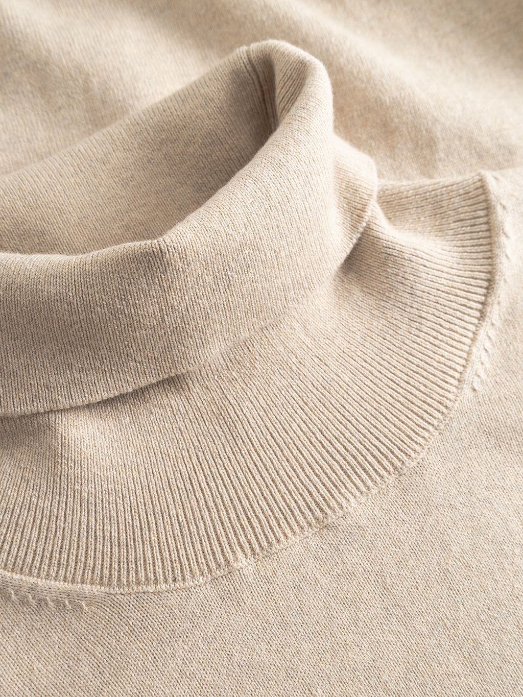 A close-up view of the Gabba Aris Prex - Sand sweater, highlighting its soft knit cashmere texture and folded roll neck collar.