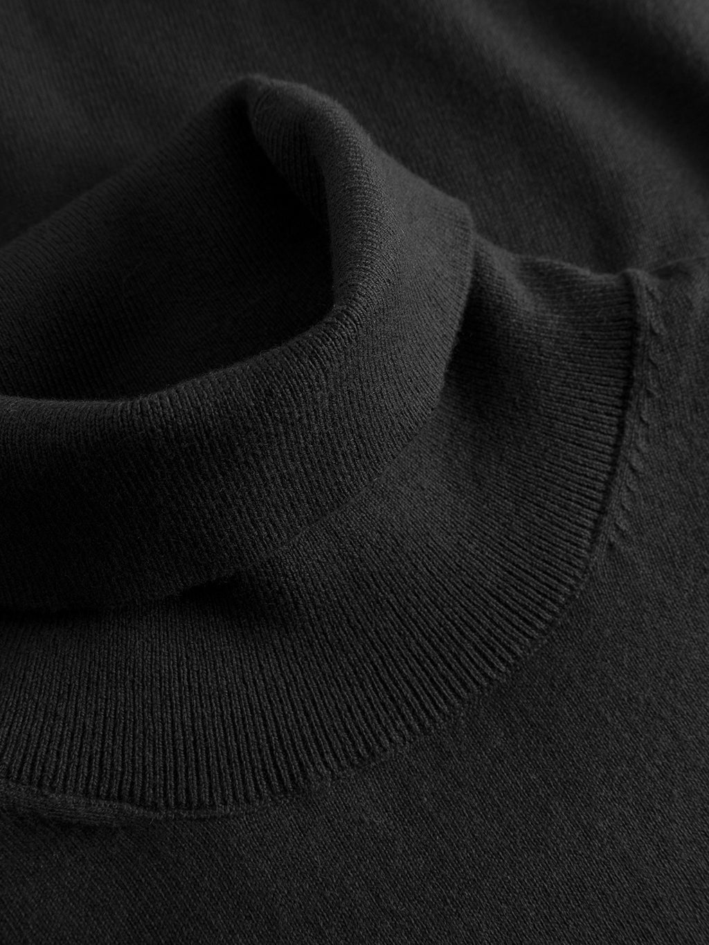 A close-up of the Gabba Aris Prex - Black sweater, showcasing its folded roll neck collar and fine knit texture.