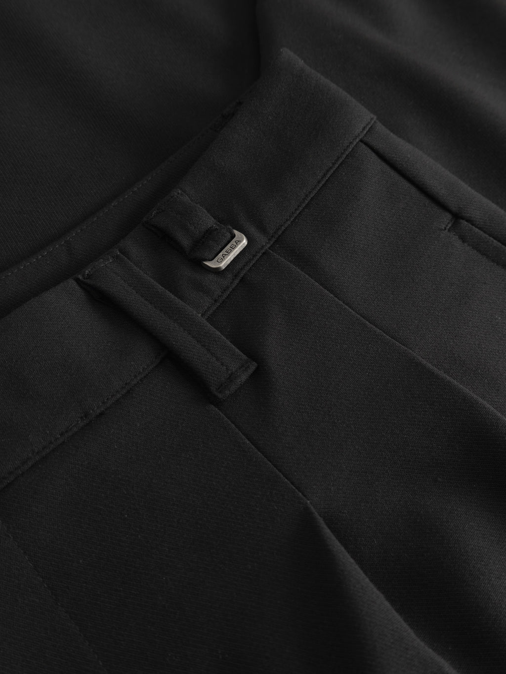 Close-up of Gabba GABfirenze Phin Cropped GRS - Black trousers, featuring a smooth, structured fabric, waistband with belt loop, metal brand tag, and front seam—ideal for formal styling or versatile wear on any occasion.