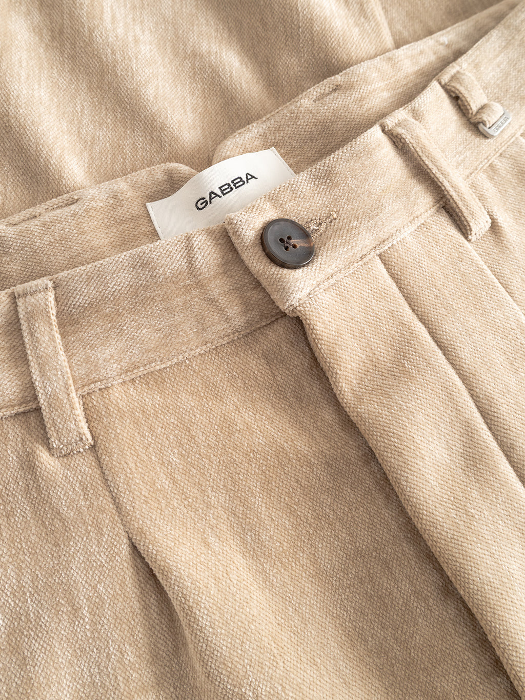 Close-up of Firenze Velour - Lt. Sand tailored pants by Gabba, featuring a button, belt loops, and a white Gabba label on the waistband for a luxurious touch.
