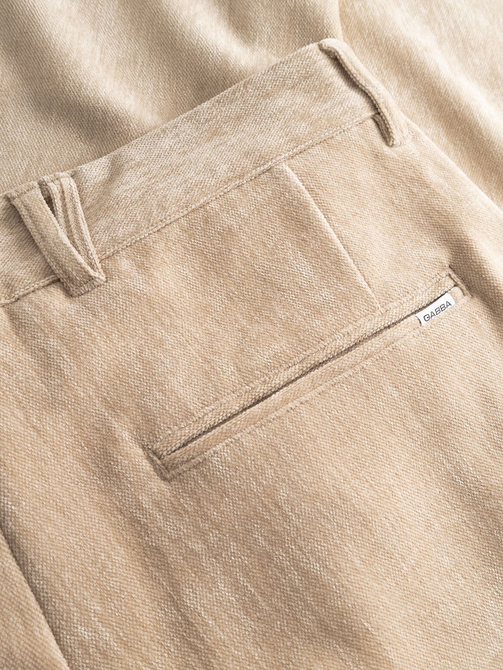 Close-up of Gabba Firenze Velour pants in Lt. Sand, highlighting the back pocket with a white Gabba label. The detailed texture and seams enhance the luxurious feel of these stylish tailored pants.