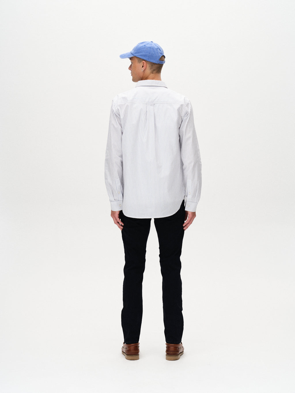 A man faces away from the camera, wearing a light blue cap, a striped shirt, and Gabbas Jones BlueBlack - Blue Black Denim slim straight fit jeans for all-day comfort, set against a plain white background.