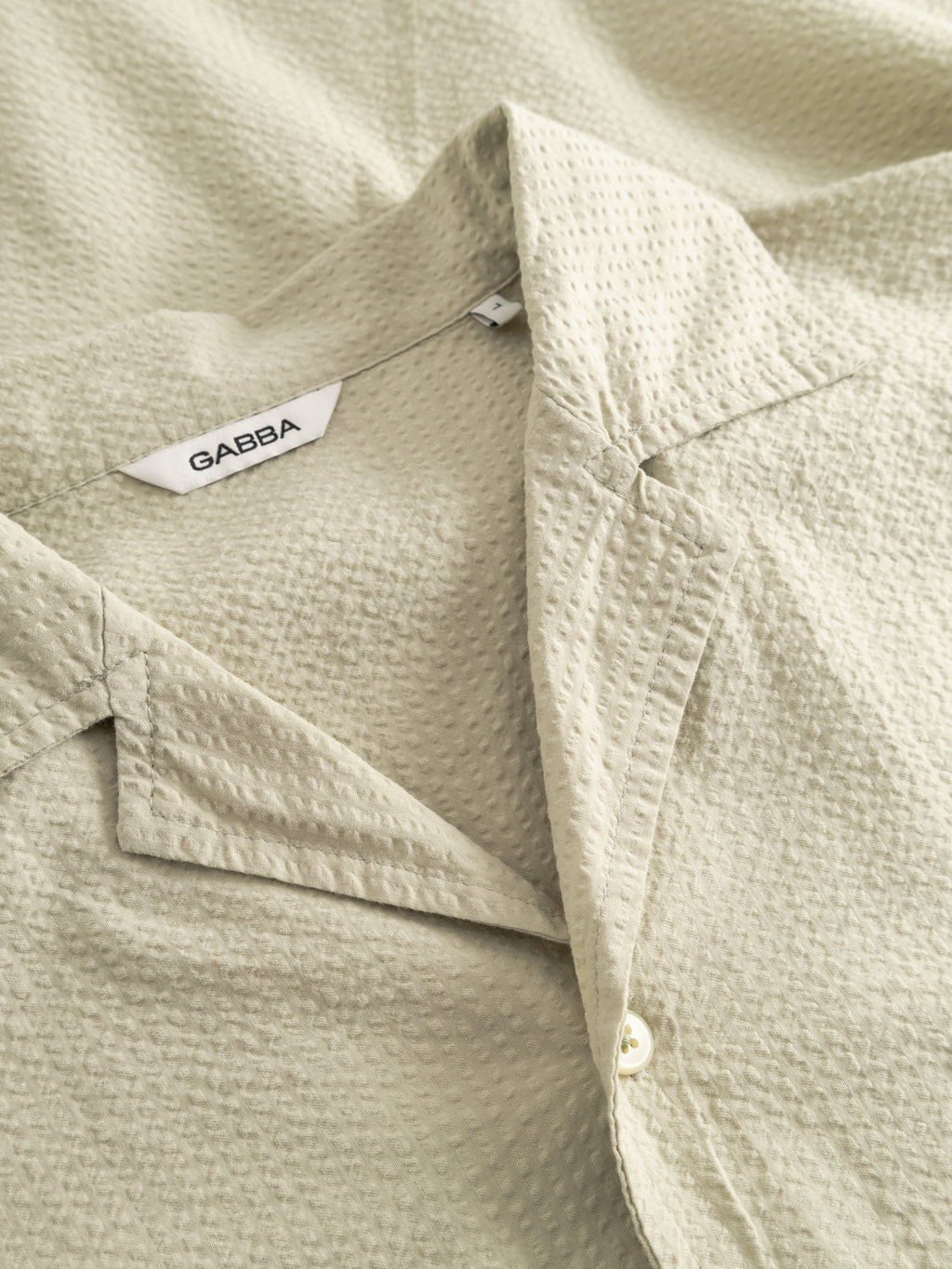 A close-up of the GABBA GABtimo Resort Ker SS Shirt in Alfa Green shows its textured cotton fabric, notched collar, single white button, short sleeves, and visible Gabba label for a relaxed resort look.