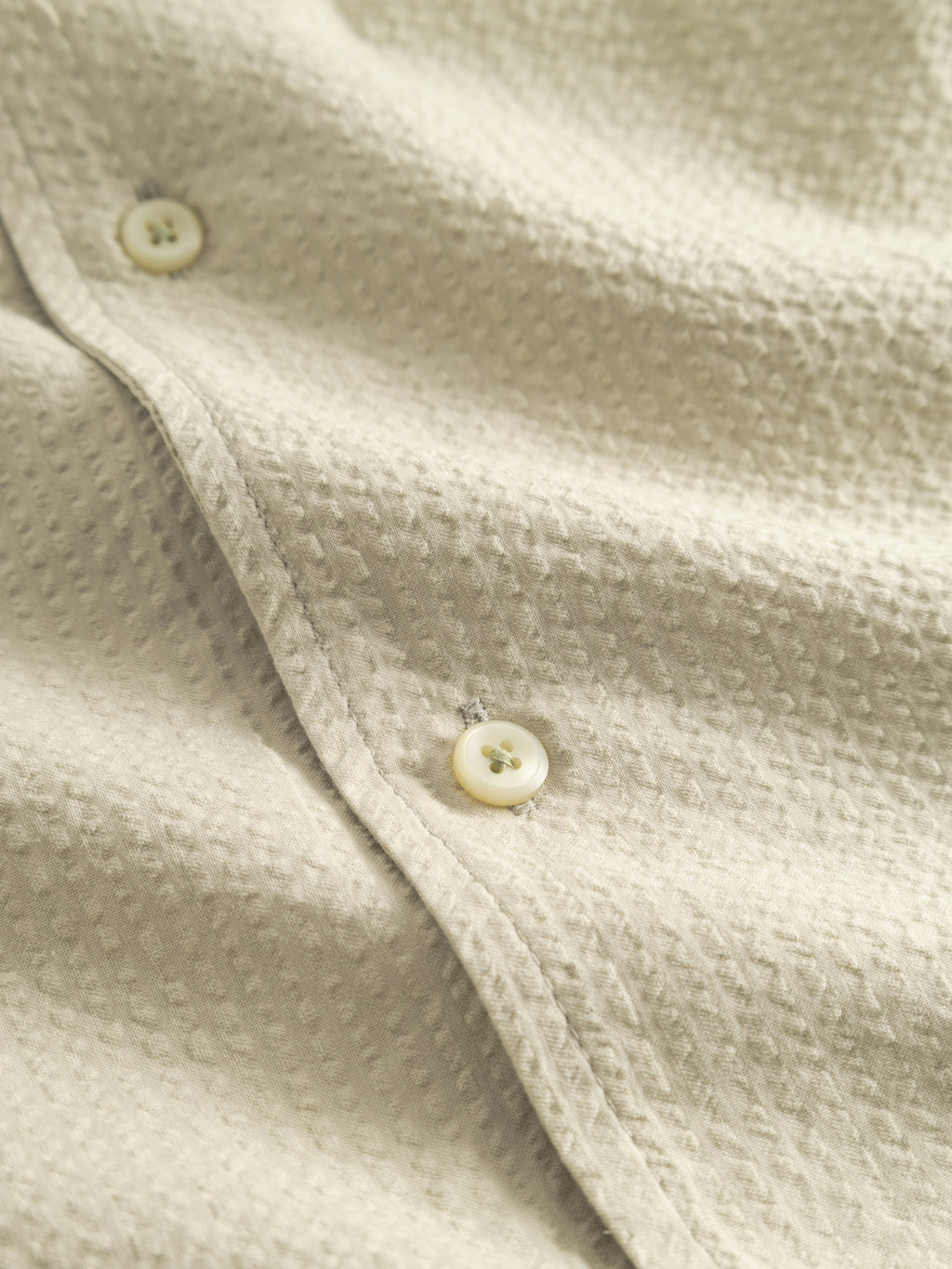 Close-up of the Gabba GABtimo Resort Ker SS Shirt in Alfa Green, highlighting two cream buttons and subtle shadows that emphasize the dimpled seersucker texture.