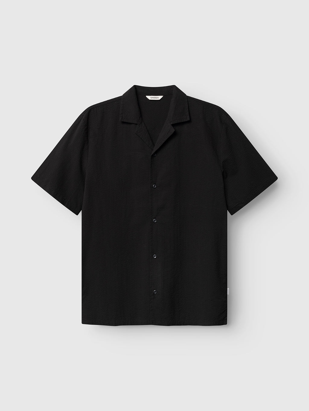 The Gabba GABtimo Resort Ker SS Shirt in black is a relaxed-fit, short-sleeve shirt with a notched collar, made from lightweight cotton seersucker, shown on a light grey background.