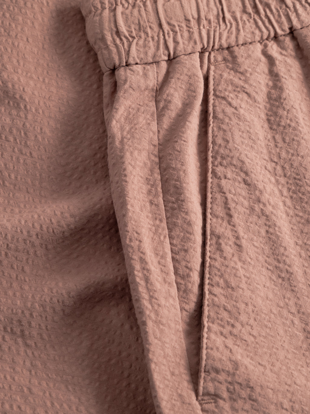 Close-up of Gabba GABtommi Ker Shorts - Wood Pink, showing textured, crinkled fabric with an elasticated waistband and side pocket, highlighting their comfortable regular fit.