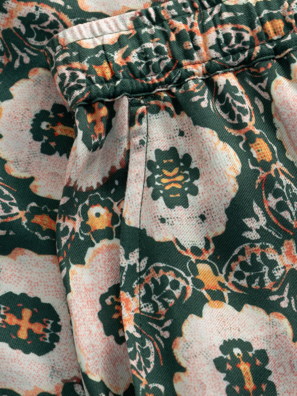 Close-up of Gabba’s GABtommi Oro Shorts in a green pattern. These floral print shorts feature gathered viscose fabric, visible stitching, and an elasticated waistband.