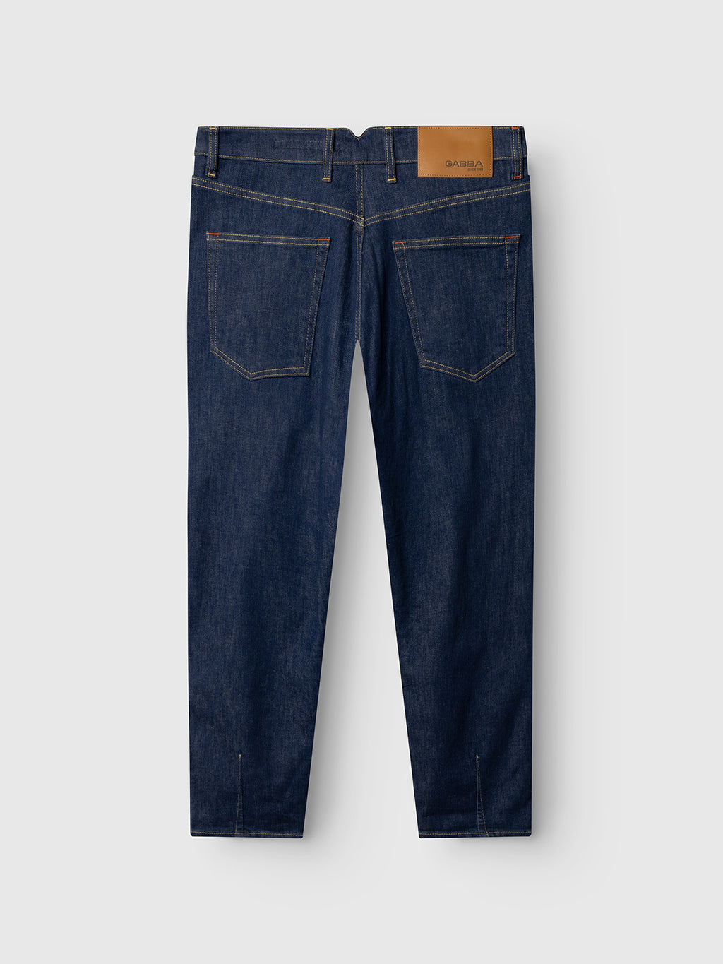 The Gabba GABalex SX Cropped Jeans in dark denim are shown from the back, with two back pockets, a tan waistband patch, visible yellow stitching, and stretchable fabric laying flat on a light gray background.