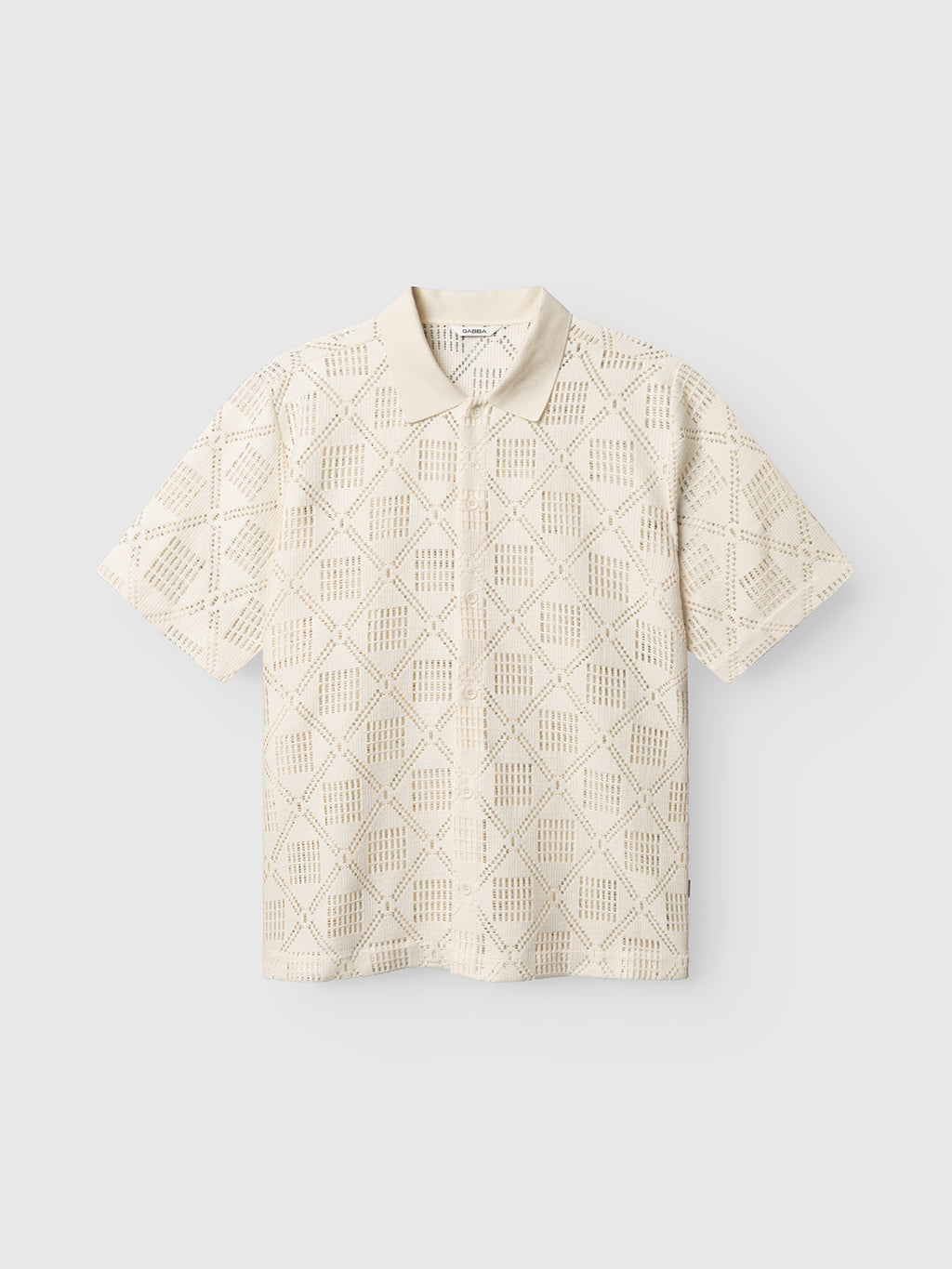 The Gabba GABsteven Croch SS Shirt GRS in Birch is a short-sleeve, cream-colored knit shirt with a collar and diamond cutout pattern, shown against a plain light background.