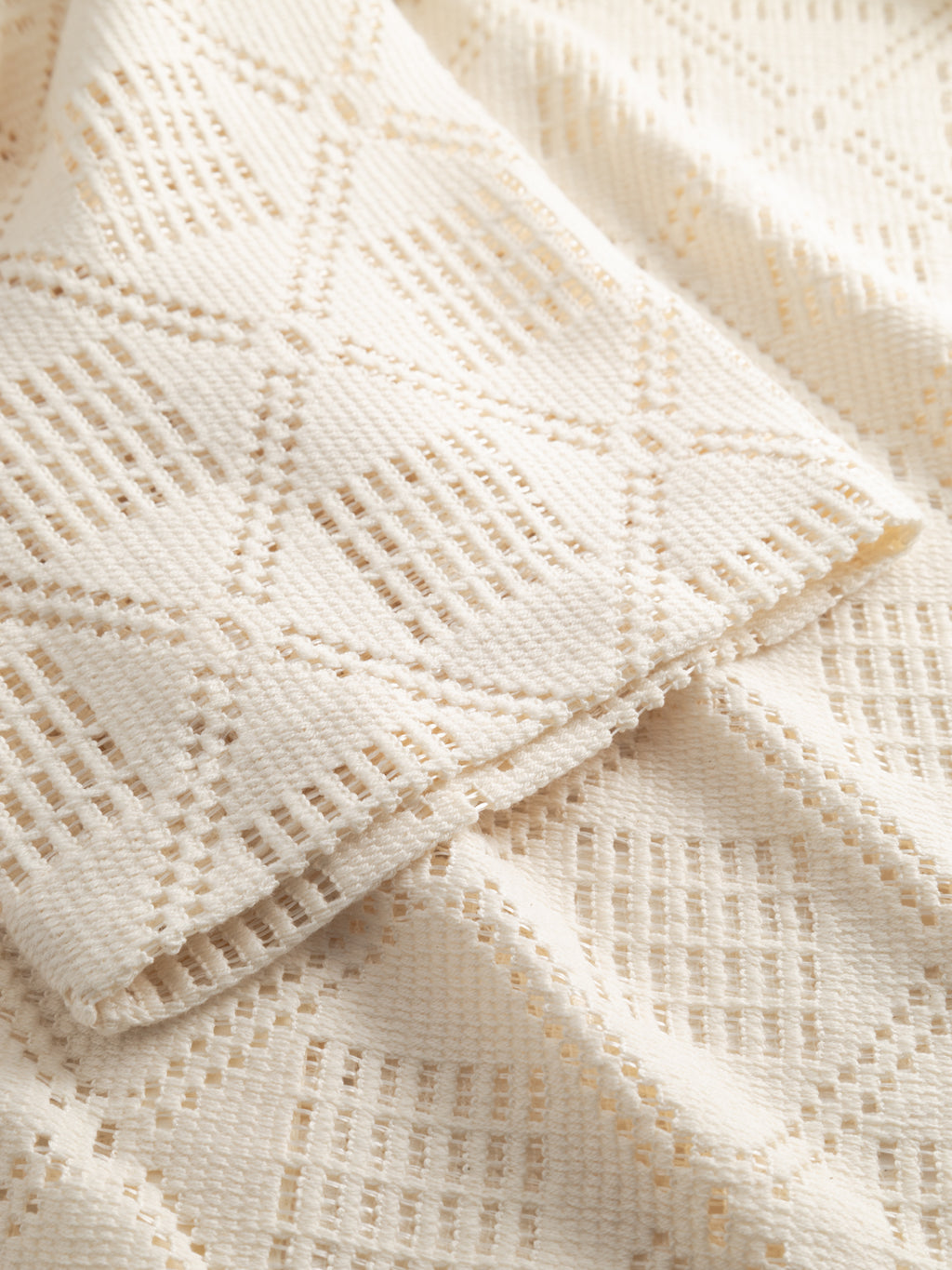 A close-up of the GABsteven Croch SS Shirt GRS - Birch by Gabba highlights its cream-colored, textured fabric with a geometric diamond pattern, soft folds, open weave sections, and intricate details.