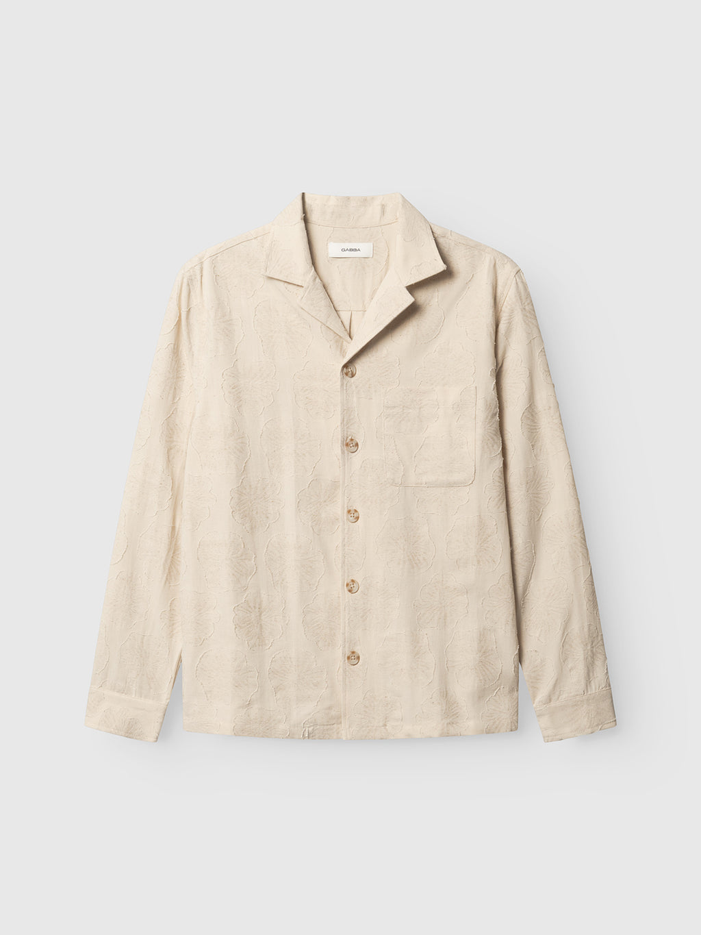 The Gabba GABaustin Reso Raw LS Overshirt in Lt. Sand is a beige jacquard-woven cotton overshirt with long sleeves, regular fit, single chest pocket, and a subtle cut-out floral textured pattern, shown on a plain light background.