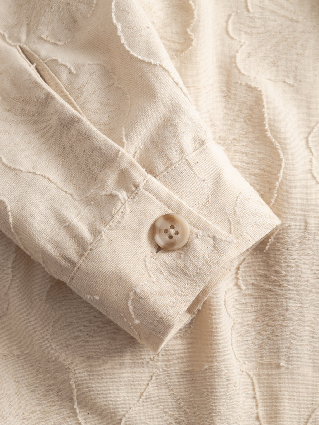 Close-up of the Gabba GABaustin Reso Raw LS Overshirt in Lt. Sand, showing the jacquard-woven cotton cuff with a subtle cut-out floral pattern, button closure, and visible stitching details.