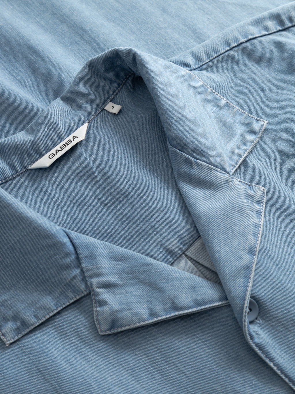 Close-up of a Gabba GABtimo Resort Denim SS Shirt in light blue, showing the collar, a partially visible button, and a white brand tag with 