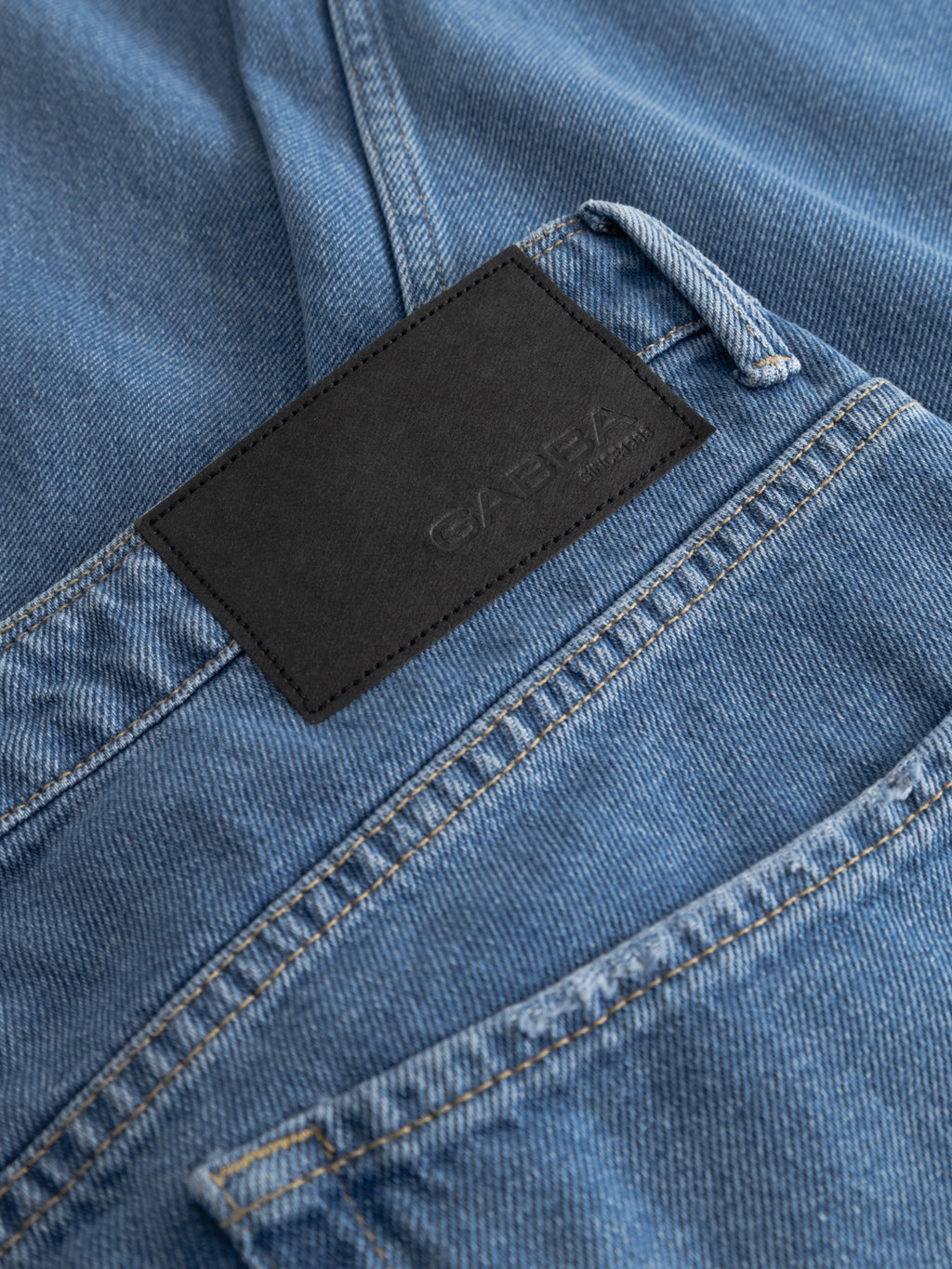Close-up of Gabba GABmax 5poc Mid Jeans in mid blue denim, featuring classic 5-pocket design, visible stitching, and a black leather patch with embossed text above the back pocket. Made from durable cotton for long-lasting wear.