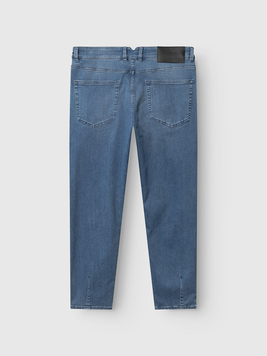 The Gabba GABalex Dhera Cropped Jeans in light blue denim are shown from the back, with two back pockets, a black leather waistband patch, and subtle seam detailing near the hems.