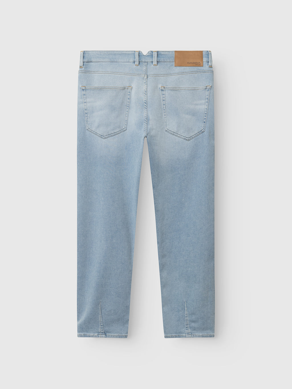 Back view of Gabba GABalex Dynamic Cropped Jeans in light blue denim, featuring two back pockets, belt loops, tan leather patch on waistband, and subtle hem seams. Made from comfort-stretch fabric and shown on a light gray background.