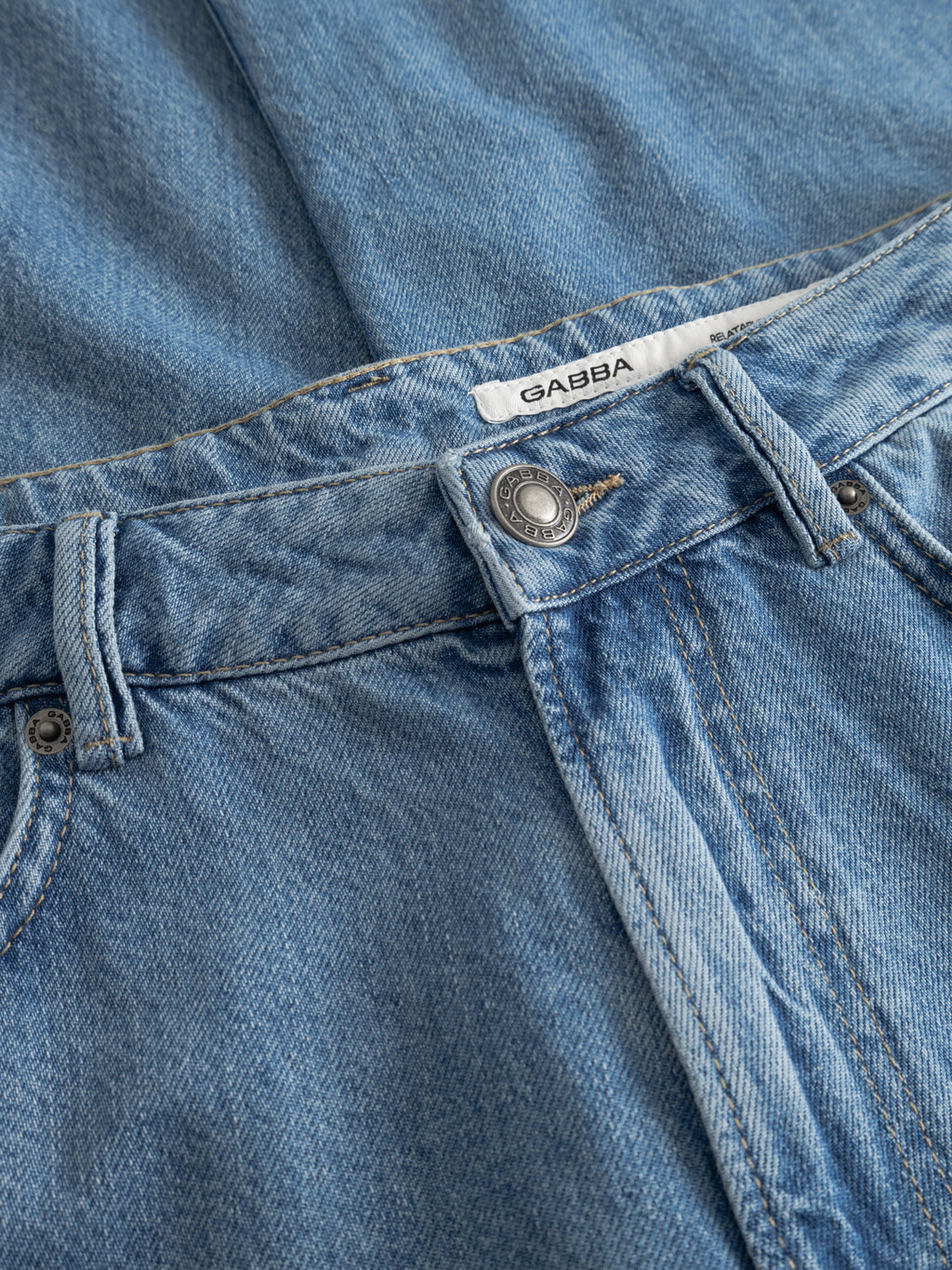 Close-up of the Gabba GABnoah Brook Jeans in denim wash, showing a metal button, belt loops, front pocket, and a white Gabba label inside the waistband that highlights their relaxed fit.