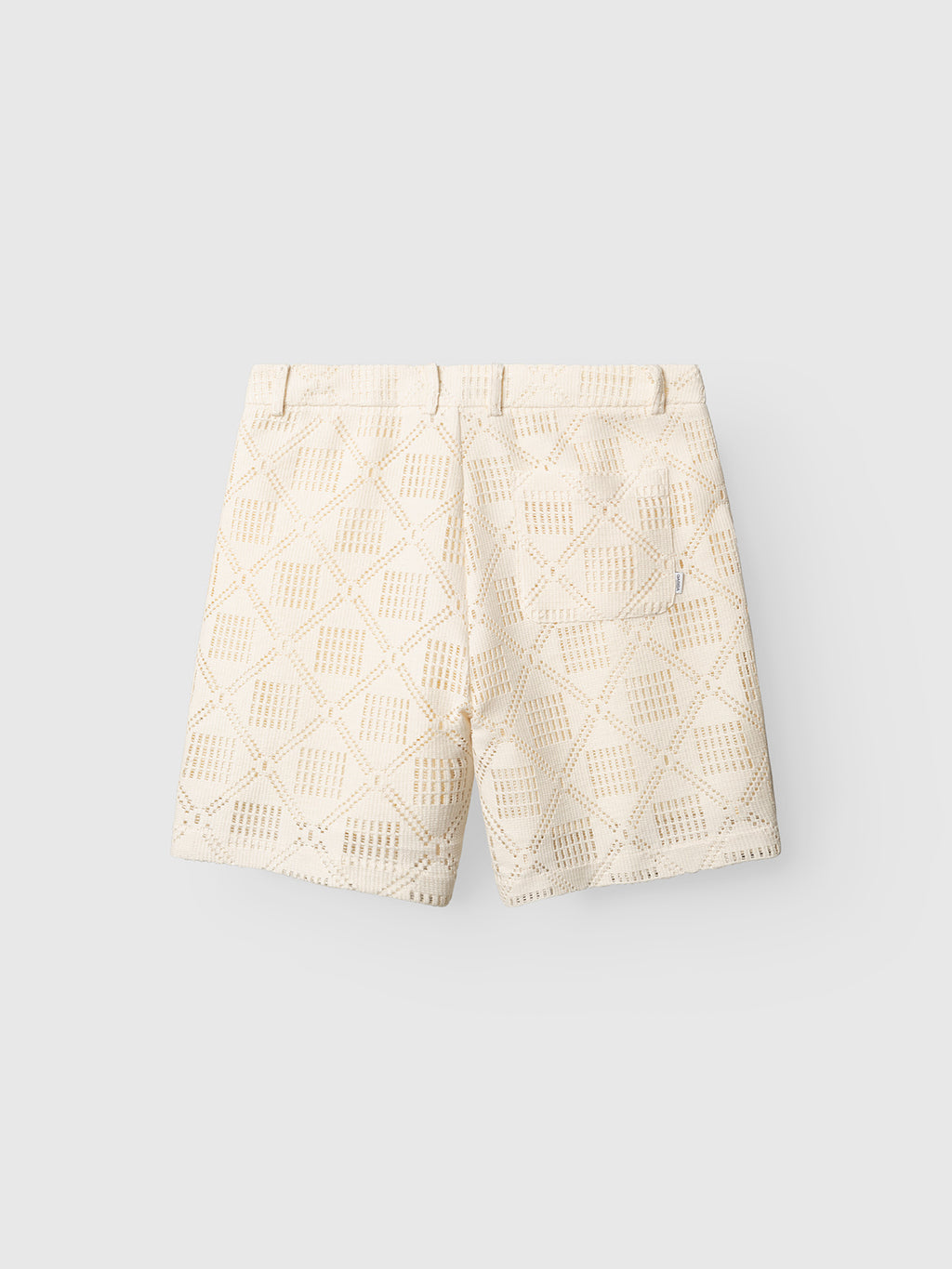 The Gabba GABjoli Ted Croch Shorts GRS in Birch are cream-colored chino shorts with a geometric crochet cutout pattern, waistband, belt loops, and a right back pocket, shown on a light gray background.