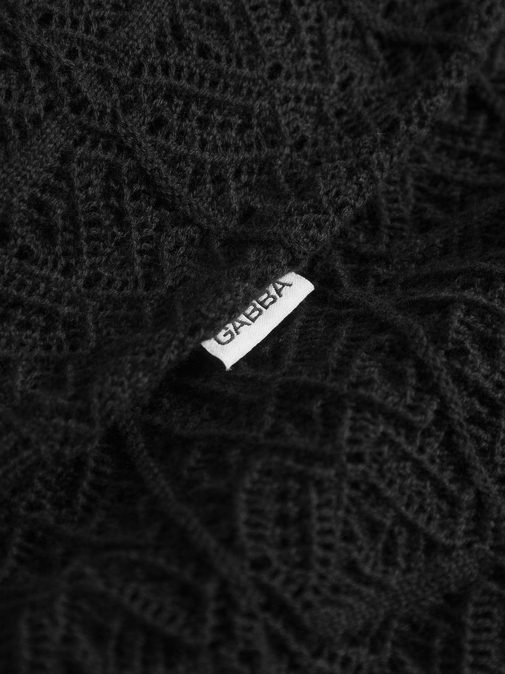 Close-up of the textured black fabric of Gabba's GABbenson Fiwi SS, featuring a partially visible white label with the Gabba brand name tucked between the folds.