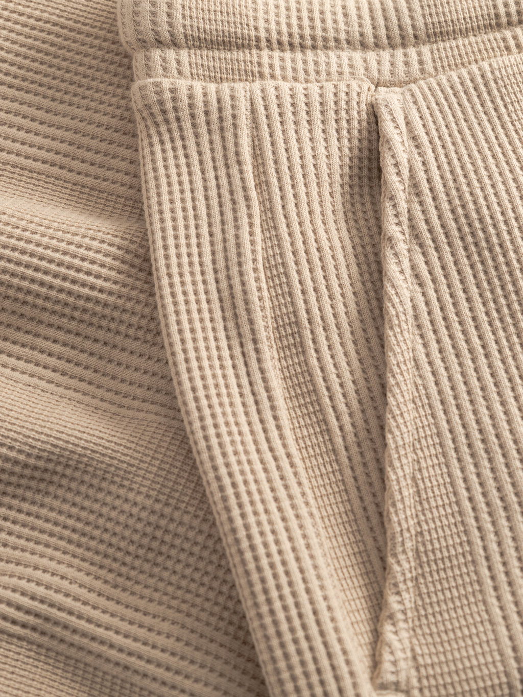 Close-up of Gabba GABtommi Wup Shorts - Humus shows beige waffle-knit fabric with visible seams, gentle folds, and a right-side pocket, highlighting the cozy texture and regular fit.