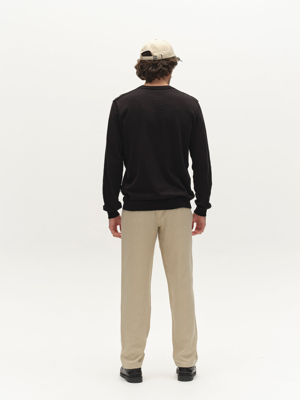 A person stands facing away, wearing beige cap, black long-sleeve shirt, Gabba GABnapoli 19 Lino Pant in Alfa Green, and black shoes against a plain white background.