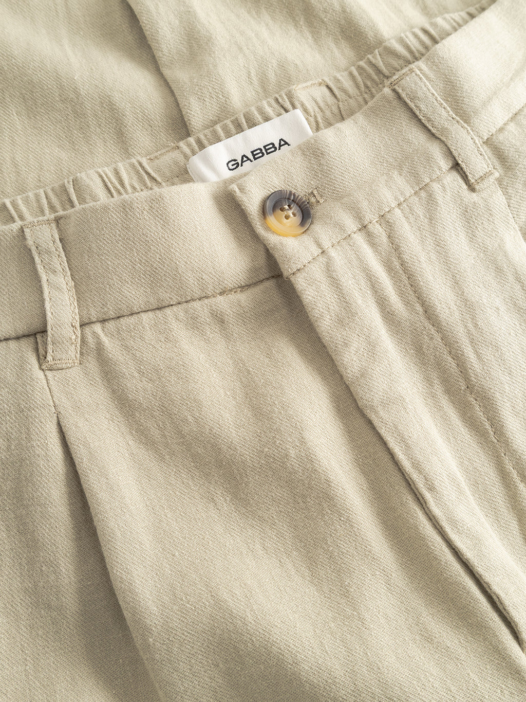Close-up of the Gabba GABnapoli 19 Lino Pant in Alfa Green, featuring a button closure, belt loops, and a white inner waistband label reading Gabba. The fabric looks soft and woven.