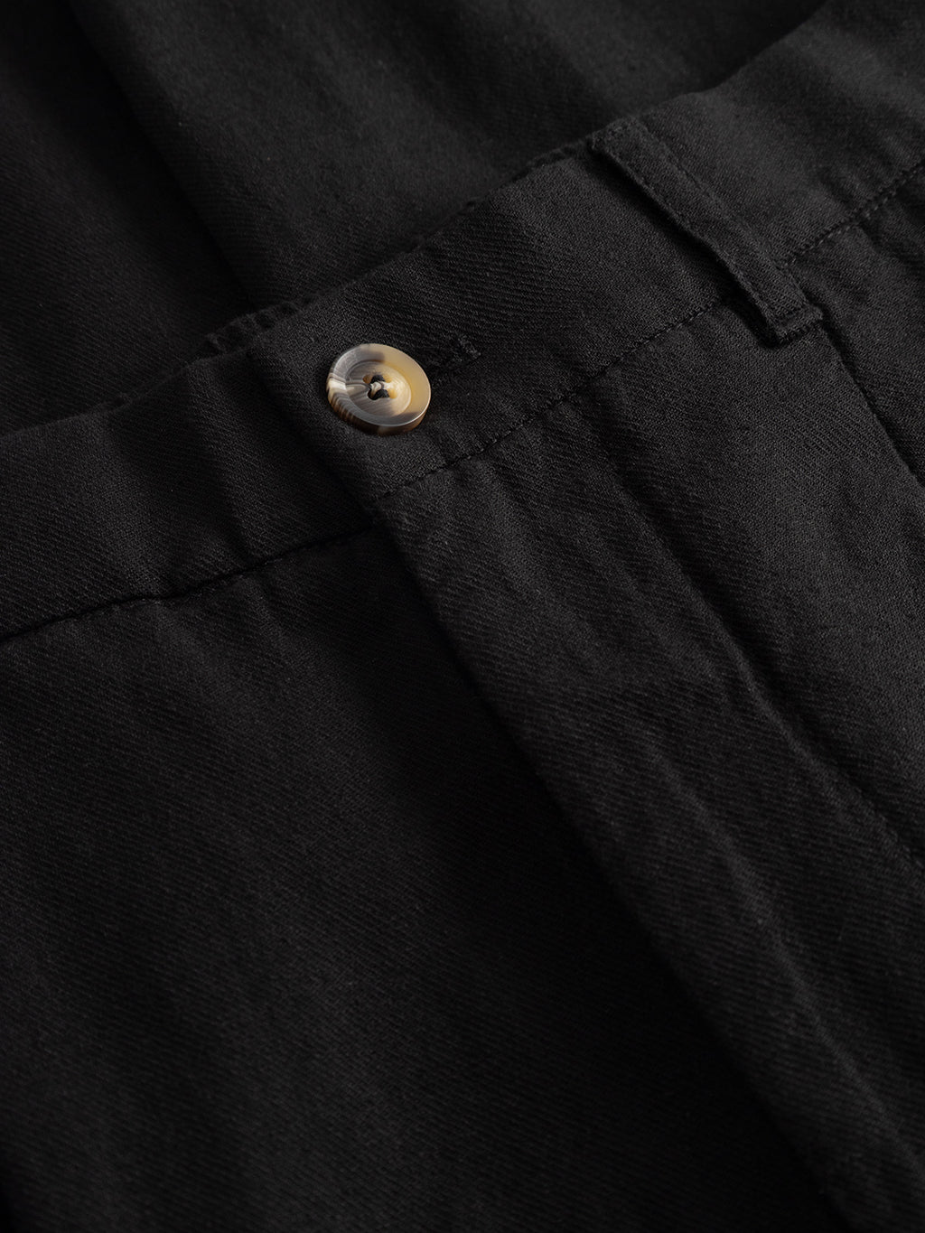 Close-up of the waist on Gabba’s GABnapoli 19 Lino Pant in Meteorite, featuring a brown button, waistband, and seam. The straight fit chino’s lightweight fabric has a smooth yet subtly textured look.