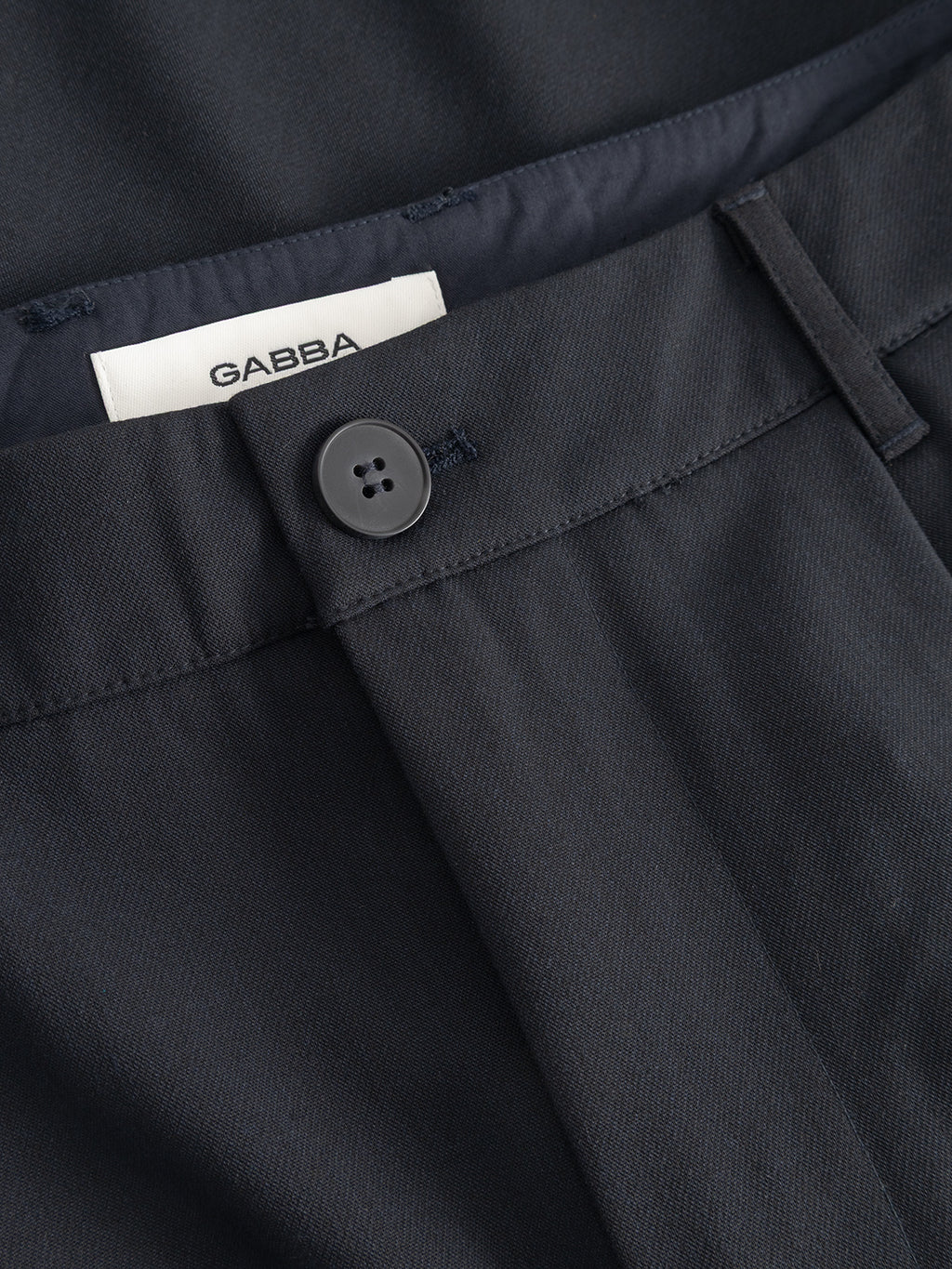 Close-up of the waistband and button closure on Gabba’s GABjoli Pas Phin Shorts GRS in Blue Black. A white GABBA label is inside, and the smooth, subtly textured fabric offers a tailored look ideal for all seasons.