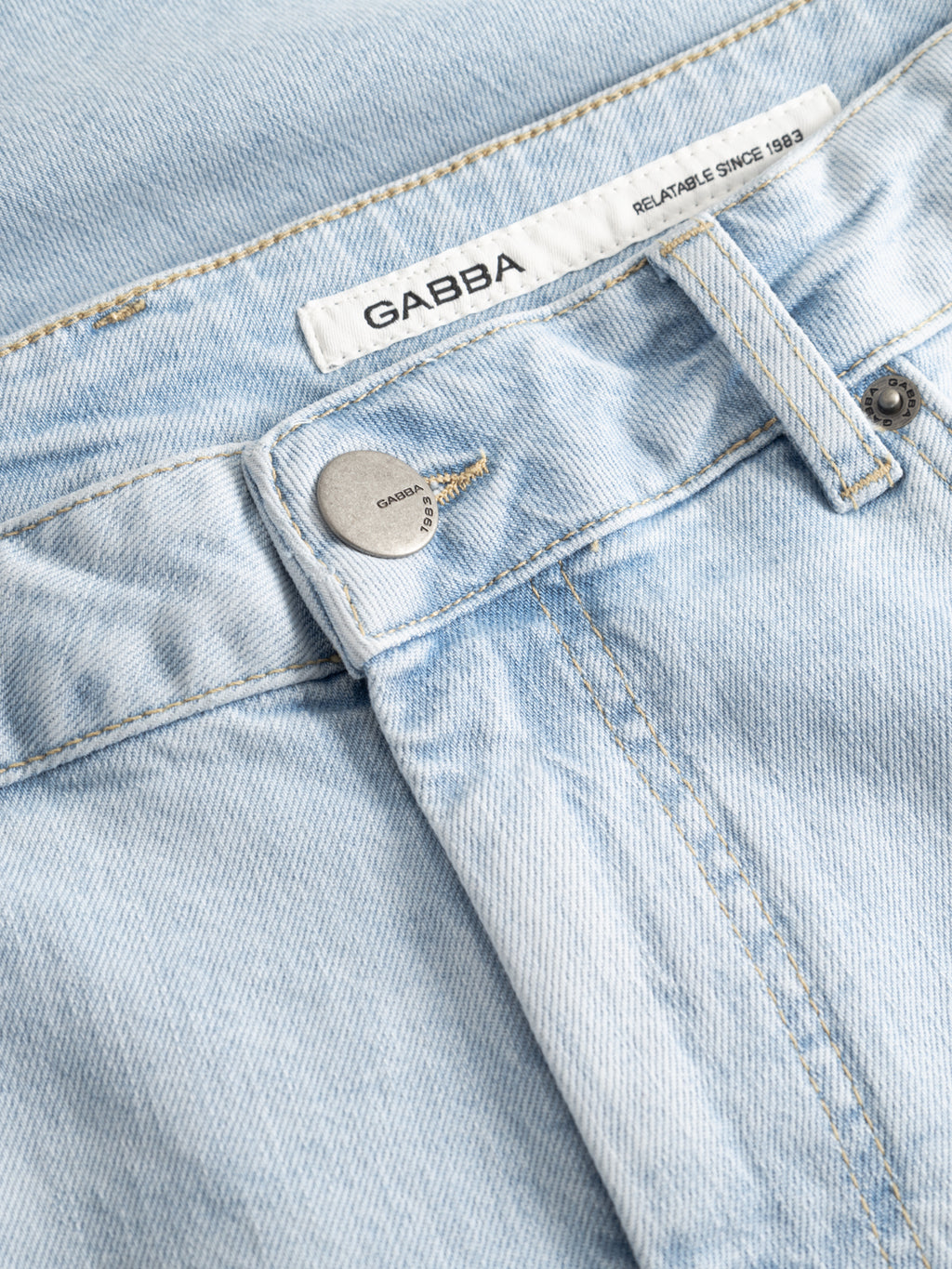 Close-up of Gabba GABmarkus Derby Shorts in light blue denim, featuring a comfort-stretch waistband, engraved metal button, belt loop, and a white 