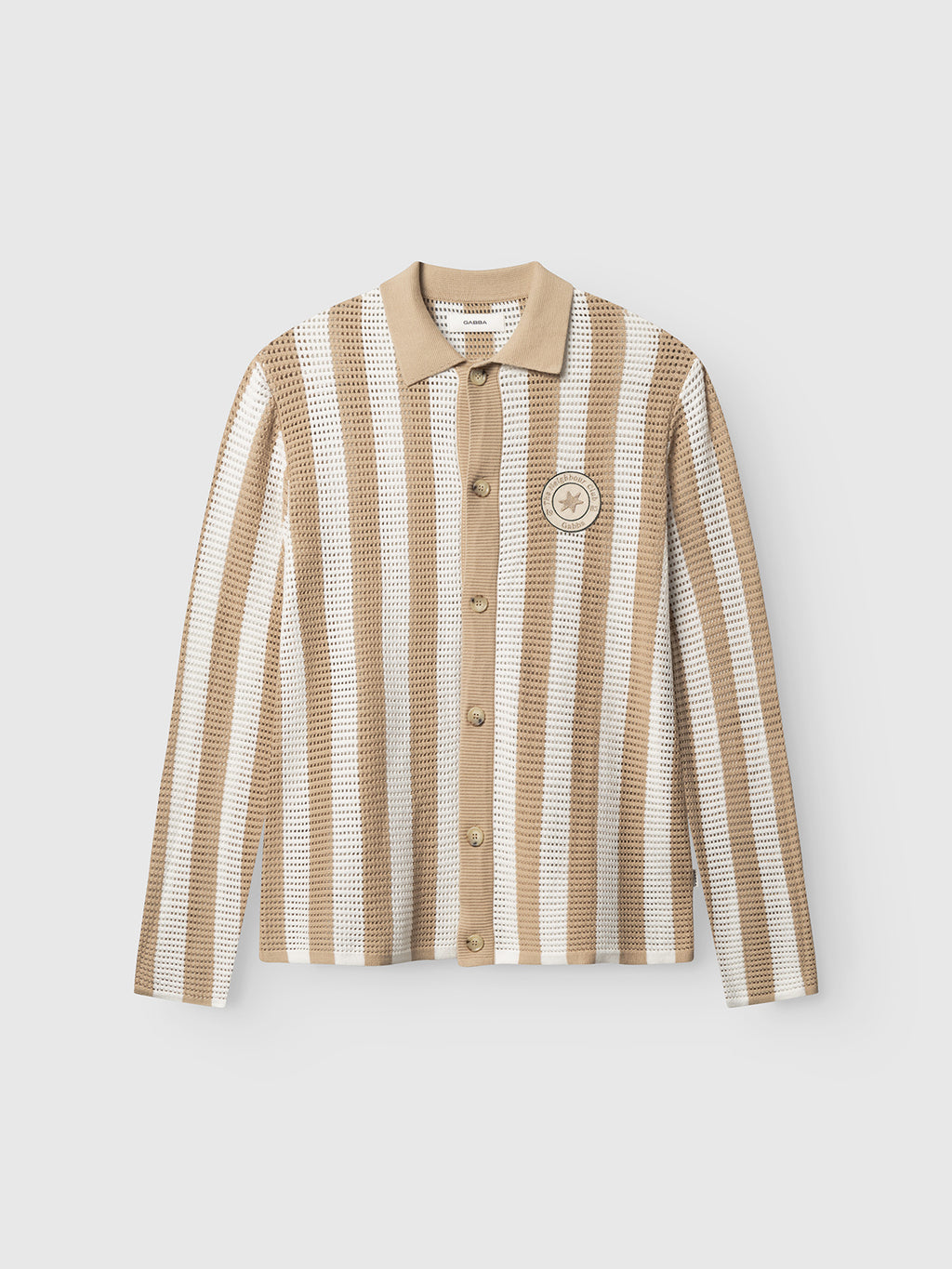 The Gabba GABdezz Bold LS Knit - Beige Stripe is a vintage-inspired, long-sleeve cotton shirt with beige and white stripes, a beige collar, star chest patch, and textured perforated knit for added style.