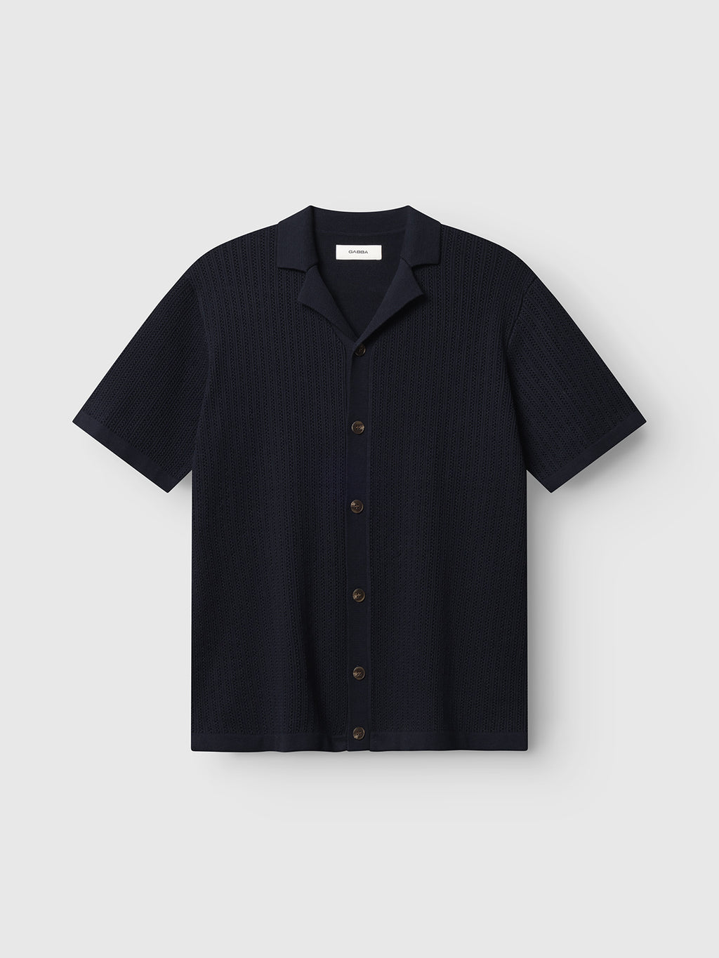 The Gabba GABgeno Resort Bride SS Knit - Navy is a short-sleeve, button-up shirt with a relaxed collar and subtle textured pattern, shown flat on a light gray background. Its minimalist design offers effortless style.