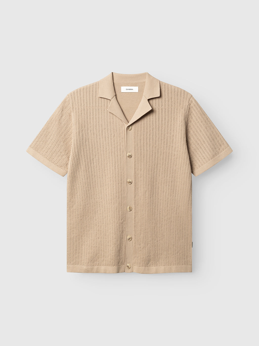 The Gabba GABgeno Resort Bride SS Knit in Sand is a relaxed-fit, short-sleeve, button-up knit shirt with a spread collar and textured patterned fabric, shown on a plain white background.