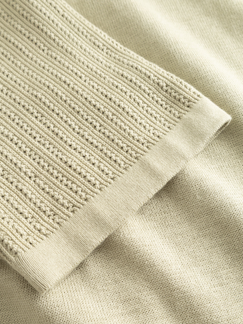 Close-up of the Gabba GABgeno Resort Bride SS Knit in light green shows two textures: ribbed, lace-like knit layered over smooth, flat-knit fabric, highlighting the contrast between detailed ribbing and plain knit.