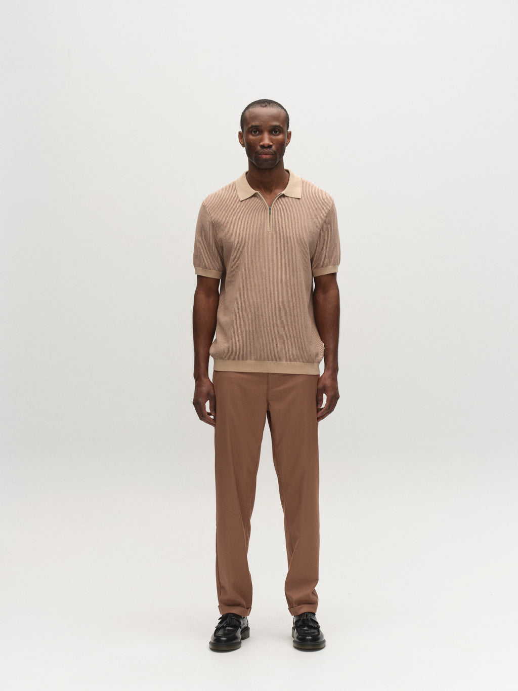 A man stands facing forward against a plain white background, wearing the Gabba GABoswald Retro SS Knit in Walnut, matching brown pants, and black shoes.