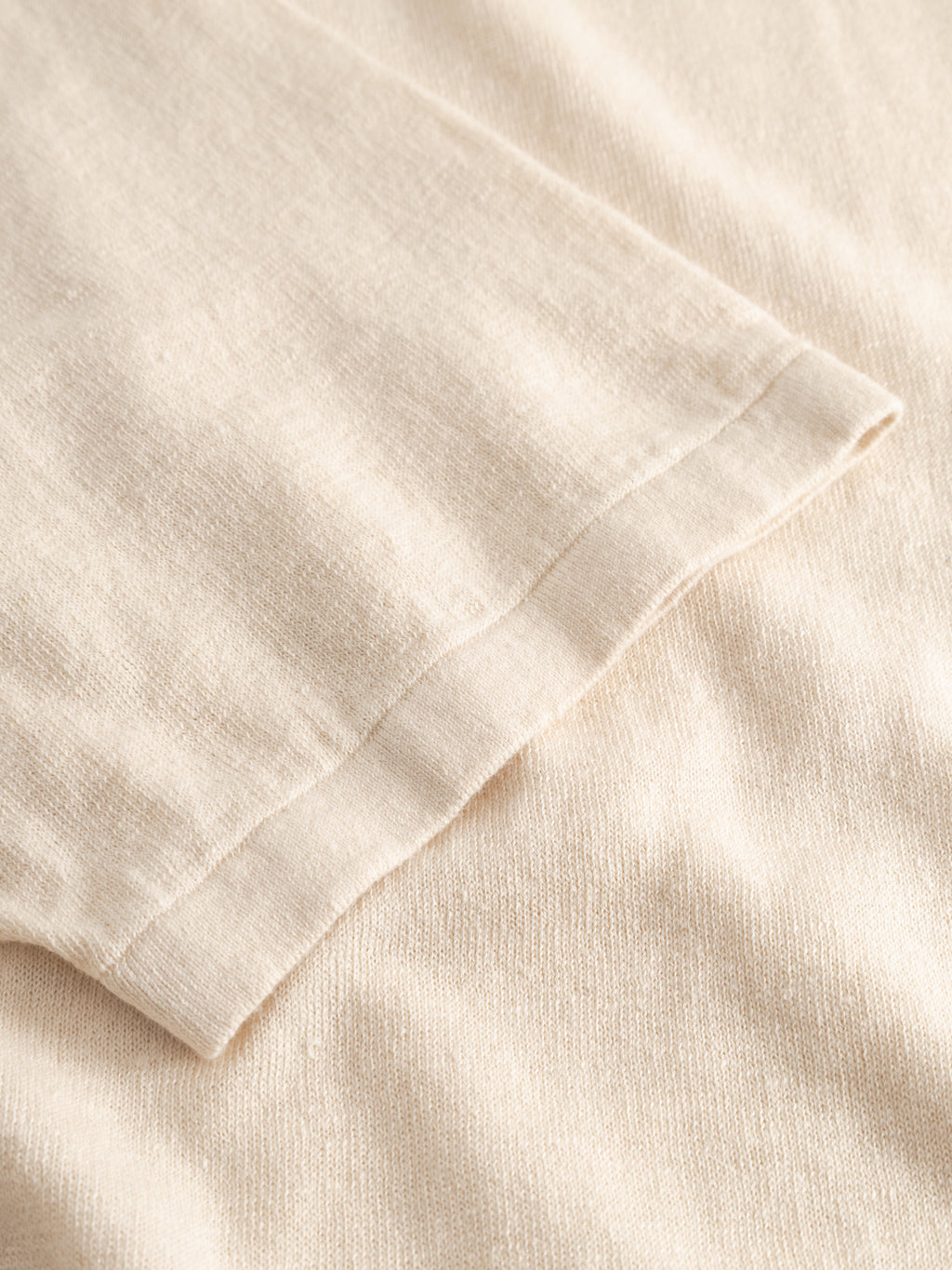 Close-up of the Gabba GABvento Dush SS Knits in Sand Mel. Shows the hem and stitching details of this soft, airy short-sleeve knit. The lightweight flat knit fabric appears smooth with a subtly textured finish.