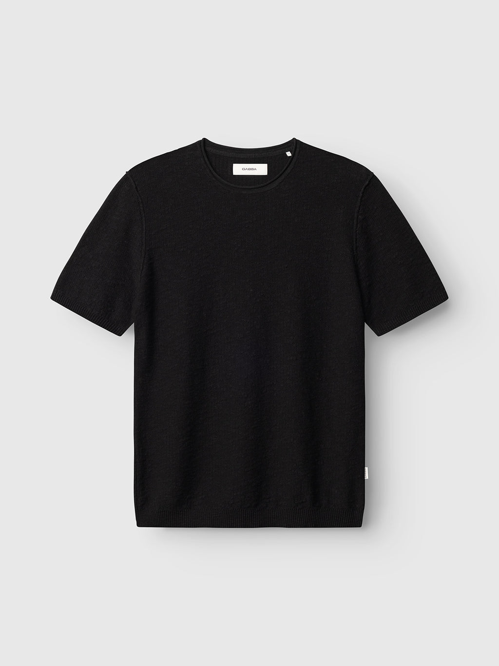 The Gabba GABnigel Alto SS Knit in black is a plain short-sleeve crewneck t-shirt with a ribbed collar, sleeves, and hem, shown against a light gray background.