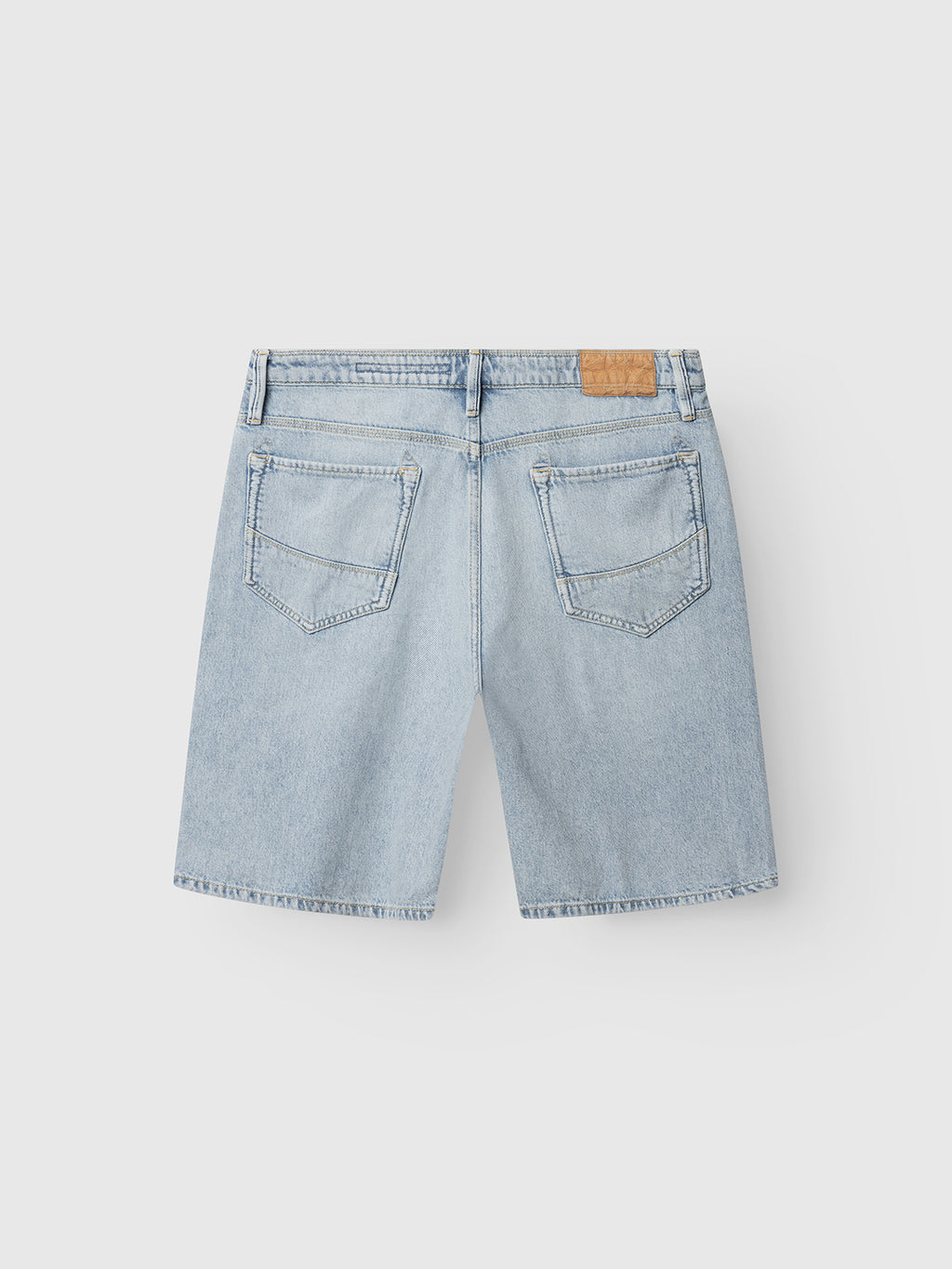 The Gabba GABmox Tona Shorts in light blue denim feature a relaxed fit, classic 5-pocket design, belt loops, and a brown leather patch on the waistband. Crafted from twill denim and shown from the back against a light background.