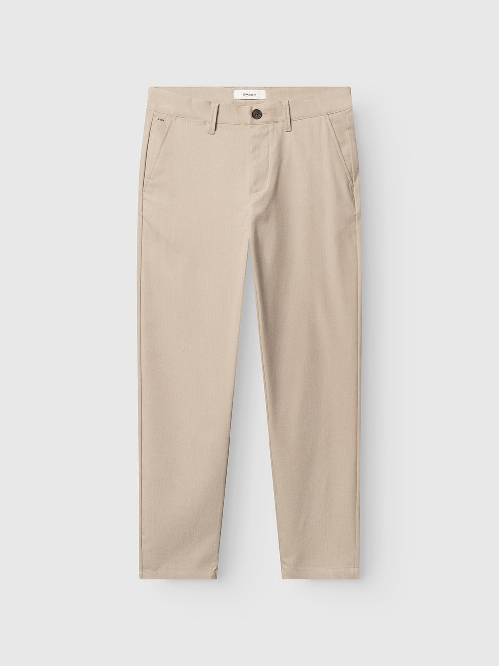 The GABpaul Deme Pant - Birch by Gabba is a beige slim-fit trouser with micro-pattern woven fabric, belt loops, button and zipper closure, plus side pockets, shown flat on a white background.