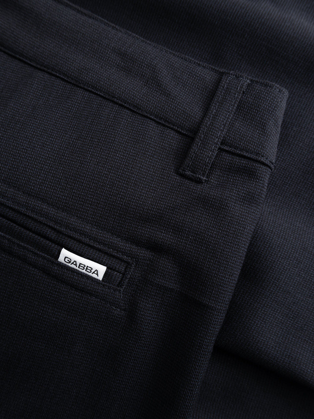Close-up of GABjet Deme Shorts in dark navy by Gabba, featuring a textured finish, back pocket with button closure, and a small white 