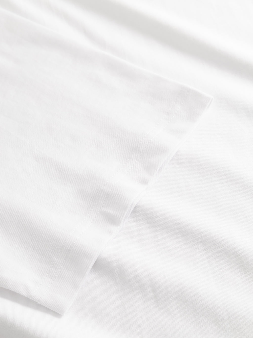 Close-up of the GABnigel Boxy Logo GOTS SS - White by Gabba, highlighting its smooth white fabric and neatly stitched hem with subtle seam details.