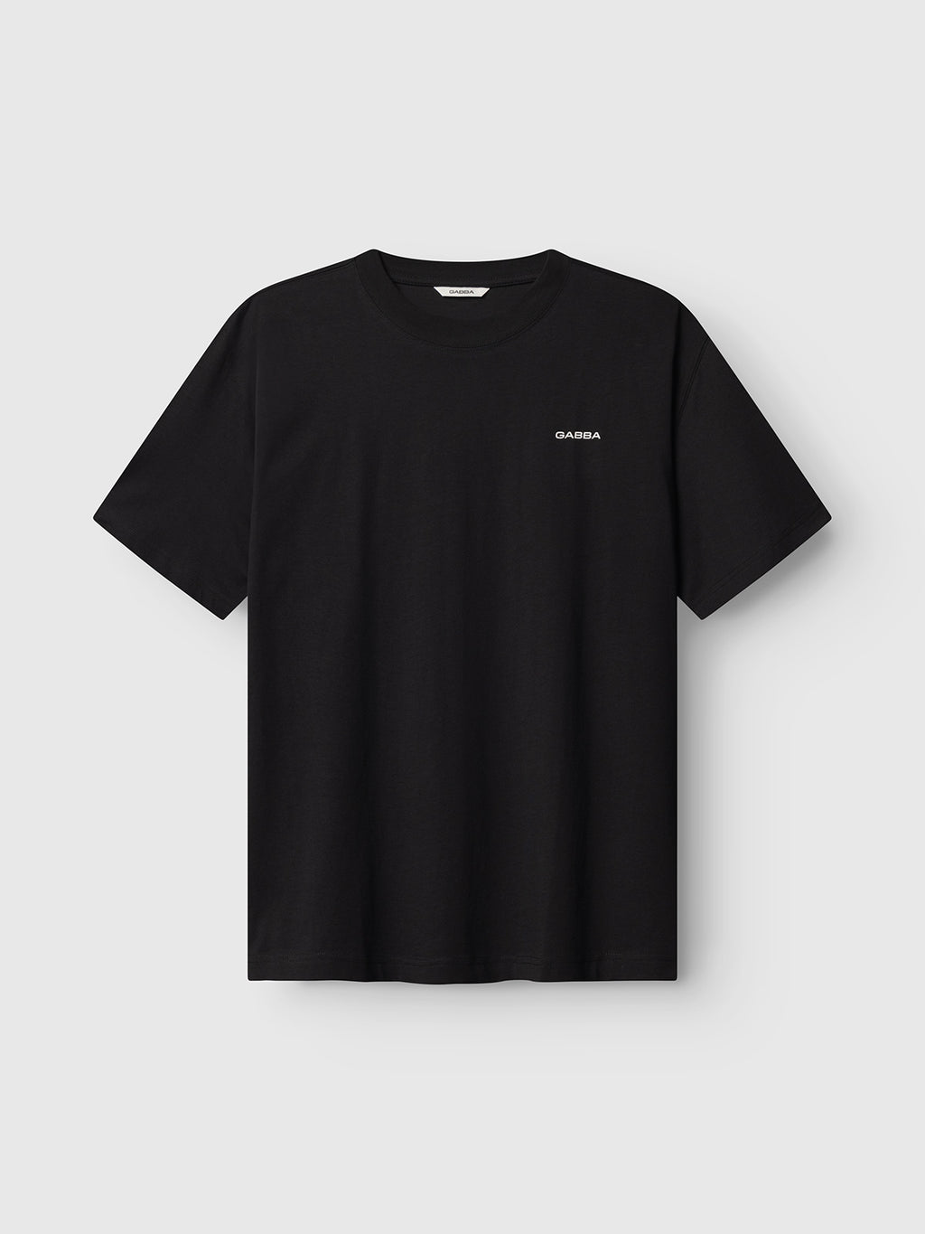 The Gabba GABnigel Boxy Logo GOTS SS in black is a short-sleeved tee with a small white logo on the left chest, shown against a light gray background.